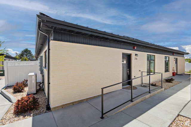 view of front of property featuring brick siding, fence, and central air condition unit