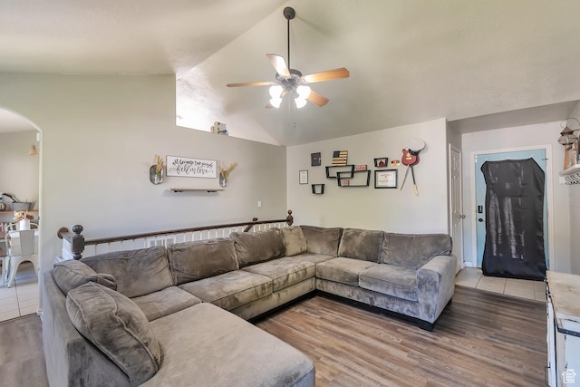 living room with arched walkways, wood finished floors, ceiling fan, and vaulted ceiling
