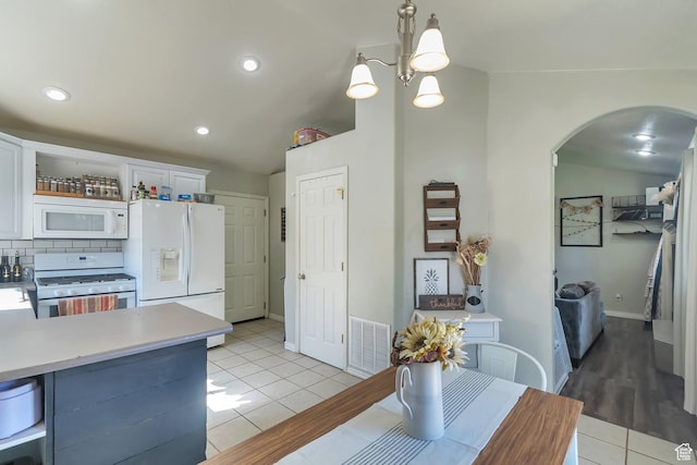 dining area featuring visible vents, baseboards, light tile patterned floors, arched walkways, and recessed lighting