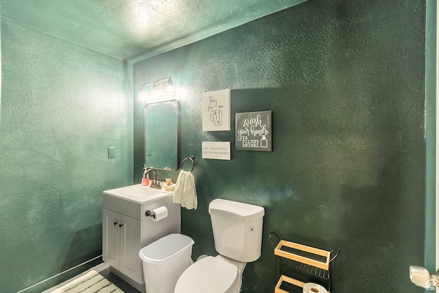 half bath featuring toilet, a textured ceiling, a textured wall, and vanity