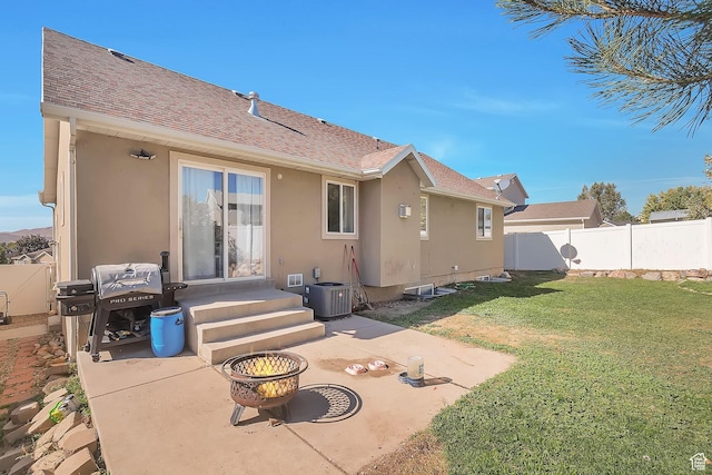 rear view of property with a yard, stucco siding, fence, and a patio area
