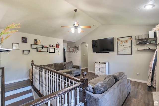 living area with arched walkways, dark wood-style floors, baseboards, and lofted ceiling