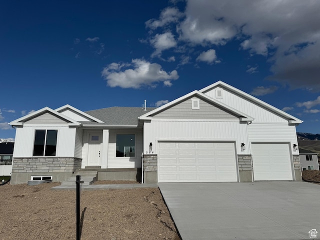 view of front of property featuring driveway, stone siding, and a garage