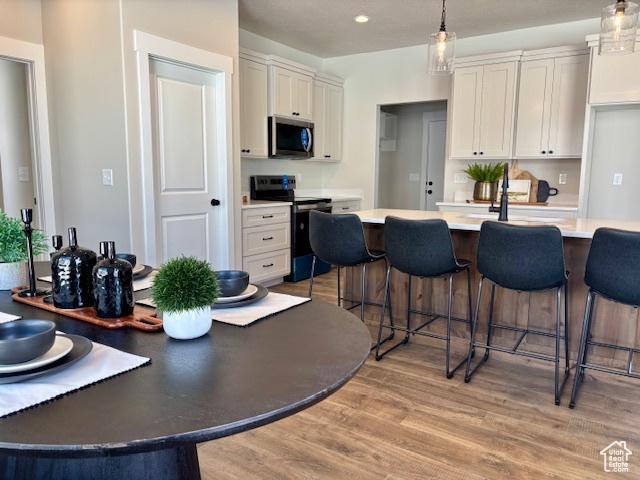 584 N 510 E, Smithfield, UT 84335 - kitchen with a kitchen breakfast bar, light wood-type flooring, light countertops, stainless steel appliances, and white cabinetry