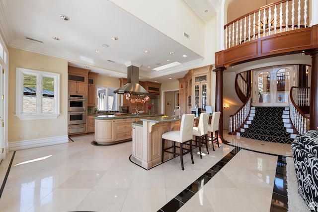 5678 E Twin Creek Rd, Emigration Canyon, UT 84108 - kitchen featuring island exhaust hood, stainless steel double oven, a breakfast bar, glass insert cabinets, and ornamental molding