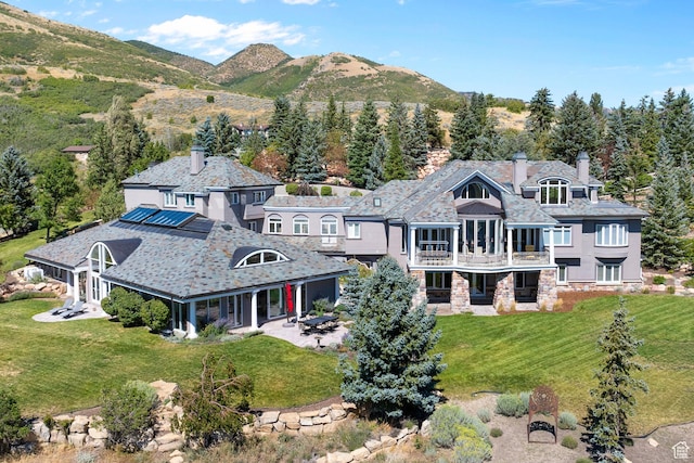 5678 E Twin Creek Rd, Emigration Canyon, UT 84108 - rear view of house with stone siding, a balcony, a patio, a high end roof, and solar panels