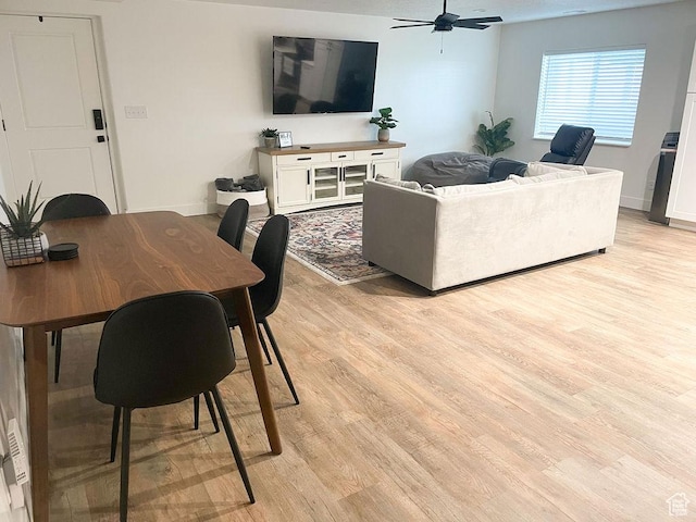 living area with baseboards, ceiling fan, and light wood-style floors
