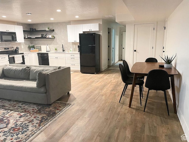 kitchen featuring open shelves, decorative backsplash, light wood finished floors, white cabinets, and black appliances