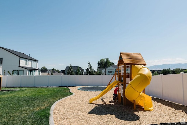view of playground featuring a fenced backyard, a mountain view, and a lawn
