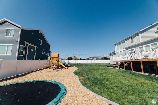 view of yard with a trampoline, a fenced backyard, and a playground