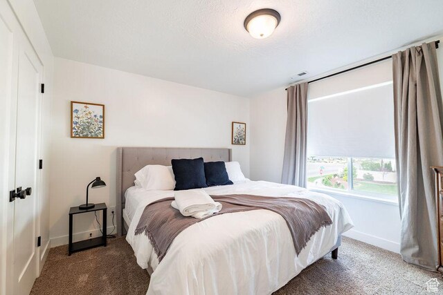 bedroom with baseboards, visible vents, carpet floors, and a textured ceiling
