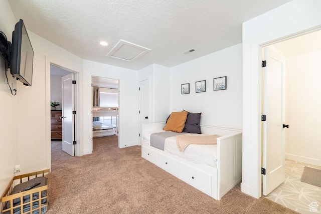 bedroom with attic access, baseboards, visible vents, and a textured ceiling