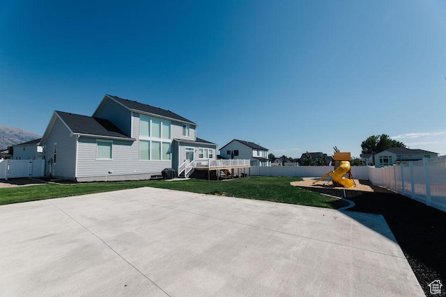 back of property with a lawn, a fenced backyard, a playground, and a patio area