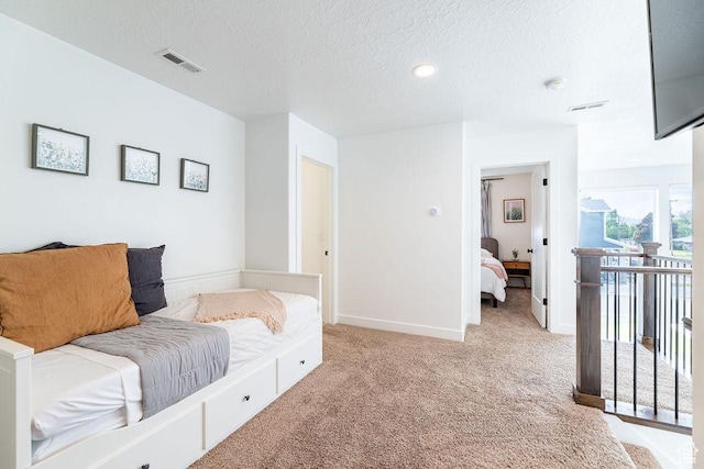sitting room with baseboards, a textured ceiling, visible vents, and light colored carpet