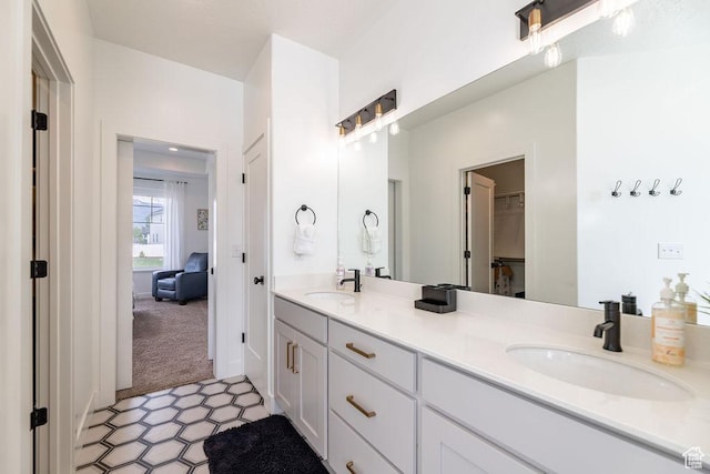 ensuite bathroom featuring double vanity, a sink, tile patterned floors, and a spacious closet