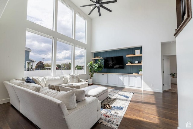 living area featuring dark wood finished floors, baseboards, a high ceiling, and ceiling fan