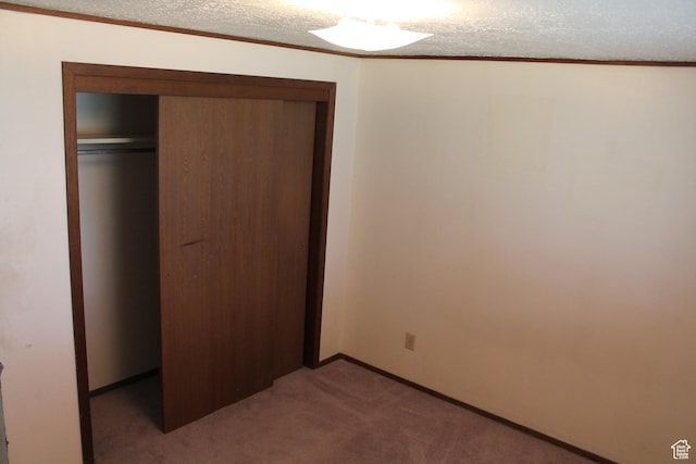 unfurnished bedroom featuring light colored carpet, a closet, baseboards, and ornamental molding