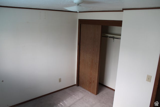 unfurnished bedroom featuring a closet, light carpet, and baseboards