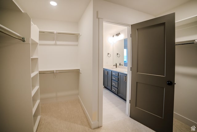 spacious closet with a sink and light colored carpet