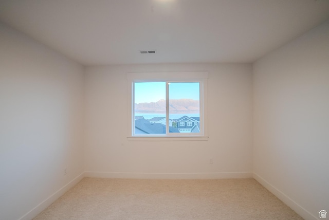 unfurnished room with light carpet, baseboards, and visible vents