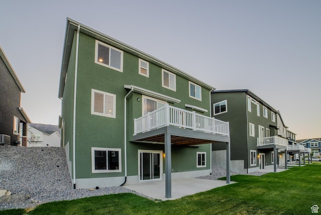 back of house with a patio area, stucco siding, central AC, and a lawn
