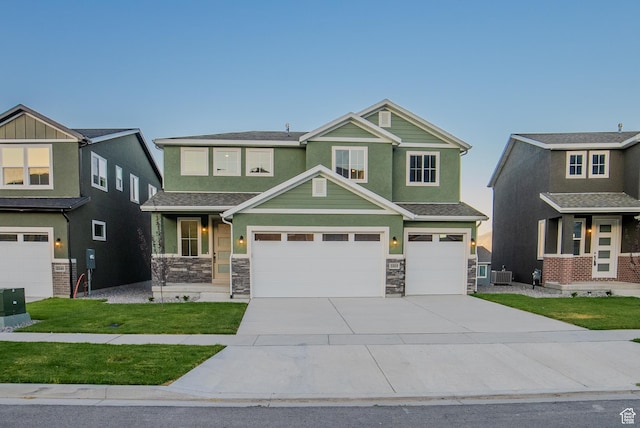 craftsman-style home featuring driveway, a front yard, a garage, central AC unit, and stone siding
