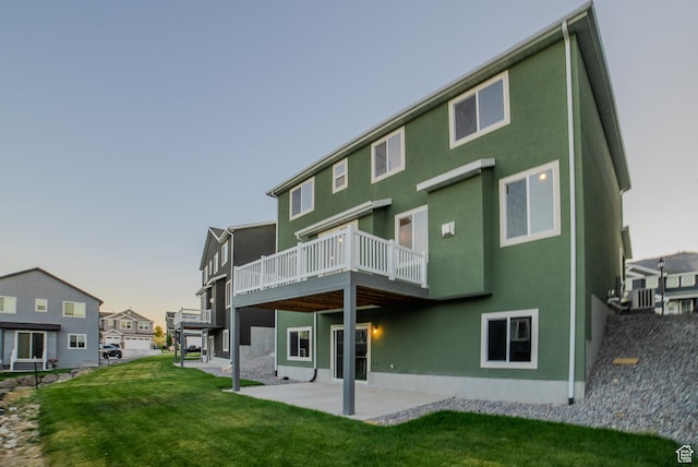 rear view of property featuring a yard, stucco siding, a wooden deck, and a patio