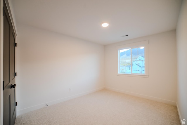 empty room featuring light colored carpet, baseboards, visible vents, and recessed lighting