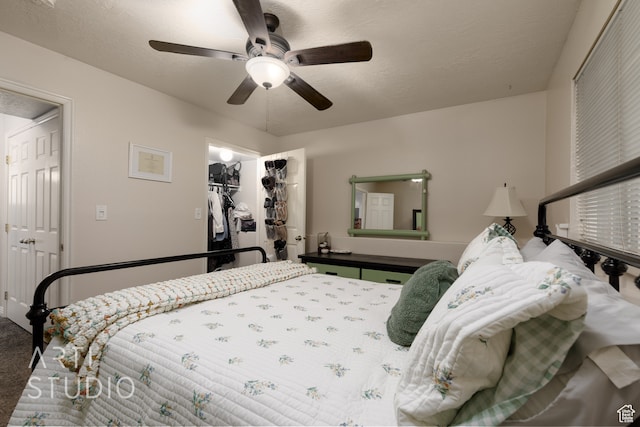carpeted bedroom with a closet, ceiling fan, a textured ceiling, and a walk in closet