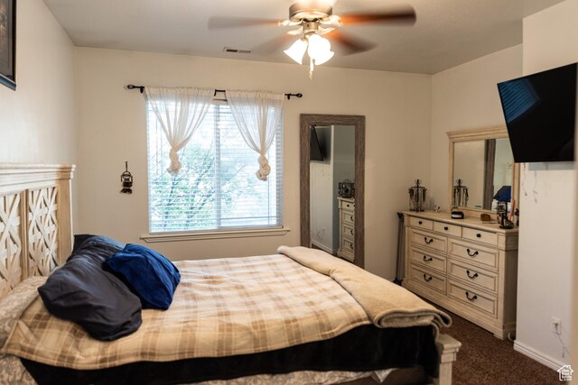 bedroom featuring a ceiling fan, visible vents, and dark colored carpet