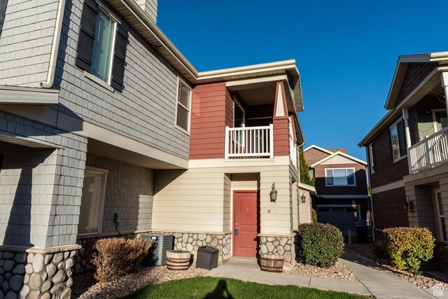 view of front of property featuring central air condition unit, a balcony, and stone siding