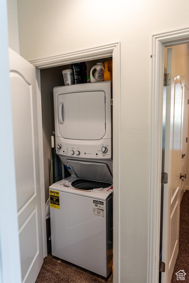washroom featuring laundry area, dark carpet, and stacked washer and clothes dryer