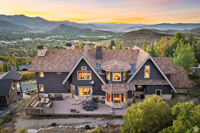 75 Hidden Oaks Ln, Park City, UT 84060 - back of house at dusk featuring an outdoor hangout area, outdoor dining area, a deck with mountain view, and a chimney