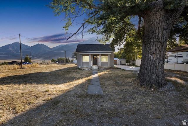 bungalow-style home featuring an outbuilding, roof with shingles, stucco siding, and fence