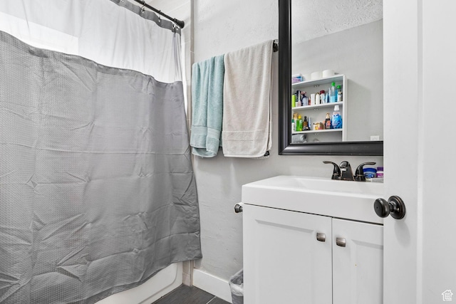 bathroom with shower / bath combo with shower curtain, vanity, and baseboards