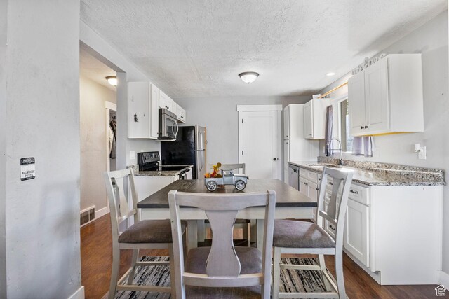 kitchen featuring a sink, stainless steel appliances, visible vents, white cabinetry, and a textured ceiling