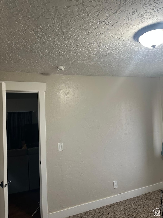 carpeted empty room featuring baseboards and a textured ceiling