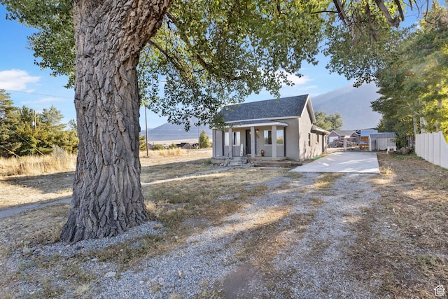 view of front of home with roof with shingles, stucco siding, covered porch, and fence