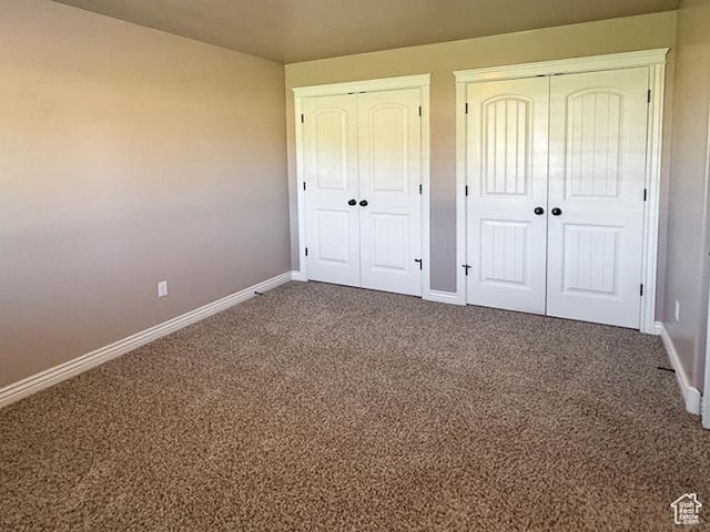 unfurnished bedroom featuring two closets, baseboards, and carpet flooring
