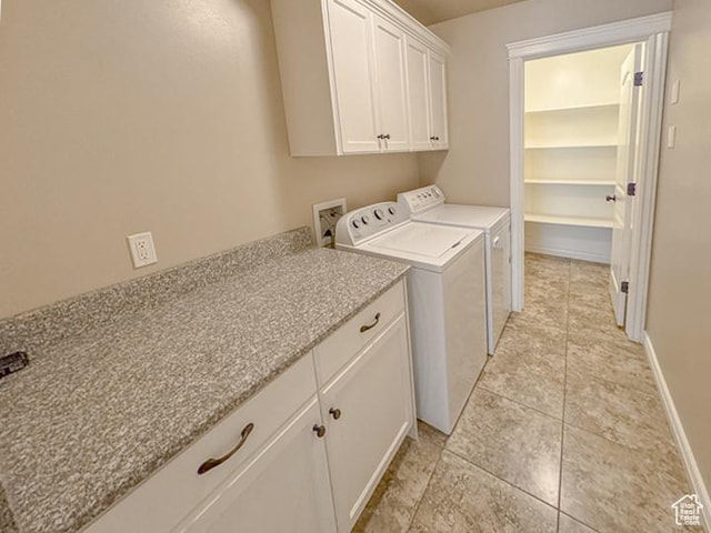 laundry room featuring light tile patterned floors, baseboards, cabinet space, and washing machine and clothes dryer