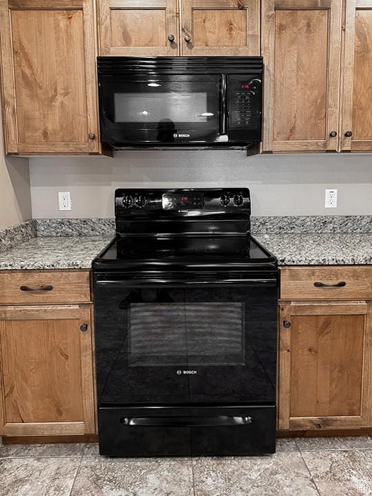 kitchen featuring light stone counters, brown cabinetry, and black appliances
