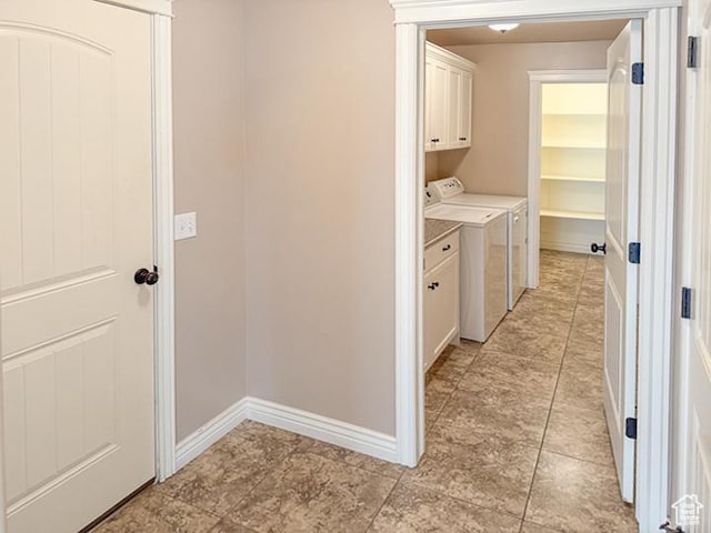 washroom featuring baseboards, cabinet space, and independent washer and dryer