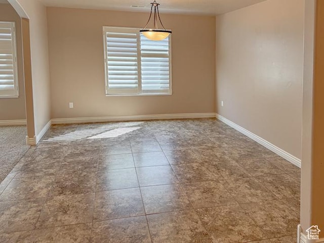 spare room featuring plenty of natural light, arched walkways, and baseboards