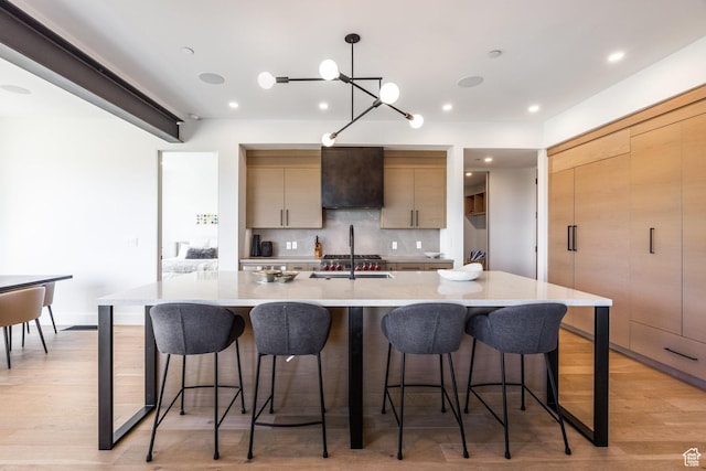 3576 Ridgeline Dr Unit 14-C, Park City, UT 84098 - kitchen featuring exhaust hood, light countertops, decorative backsplash, a sink, and a breakfast bar