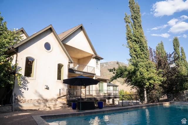 exterior space featuring a fenced in pool, a balcony, stucco siding, and fence