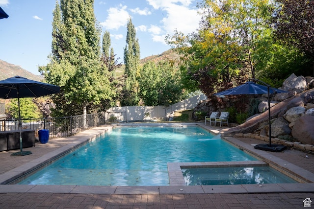 view of swimming pool with a pool with connected hot tub, a patio, a fenced backyard, and a water slide