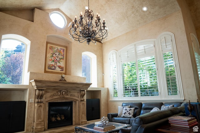 living area with high vaulted ceiling, an inviting chandelier, and a glass covered fireplace