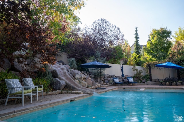 view of pool featuring fence, a patio area, a water slide, and a fenced in pool