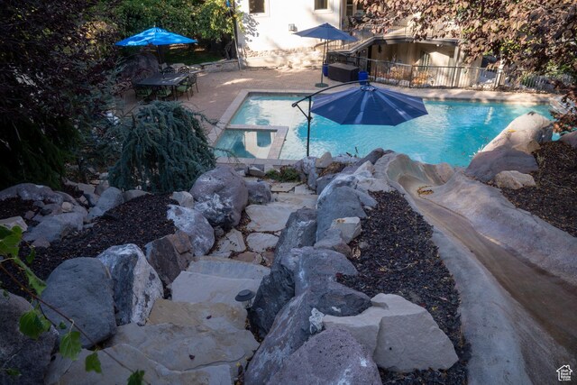 view of pool with a patio area, a pool with connected hot tub, and fence
