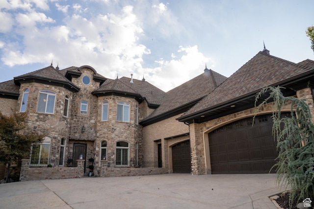 french provincial home featuring an attached garage and concrete driveway